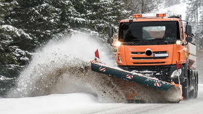 Snowplow clearing the snow off of the side of the road.