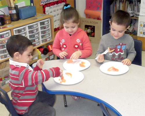 Photo: Group of children eating food at a table.