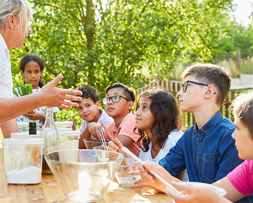 Photo: Students and teacher use a heated plate for cooking outdoorss.