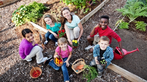 Children and adult in raised bed garden.