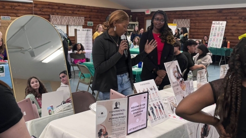 Two people at a display table, next to a full-length mirror.