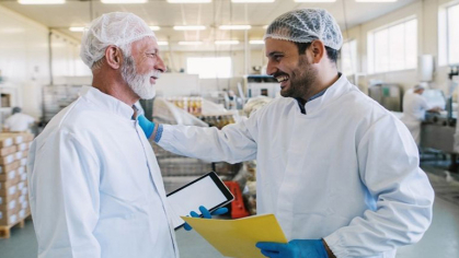 Two people talk happily as they discuss the successful new HACCP plan they came up with.