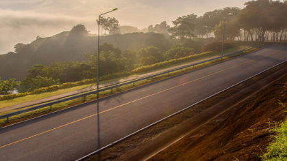 A long stretch of road is in view during sunset.