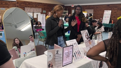 Two people at a display table, next to a full-length mirror.