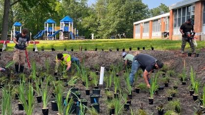 Several people building a rain garden behind a school.