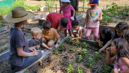 An adult and several children working in a garden.