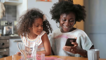 A mother and her daughter looking at a phone.