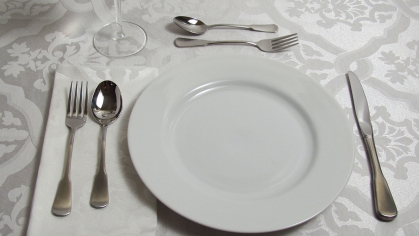 White plate on tablecloth, place setting.