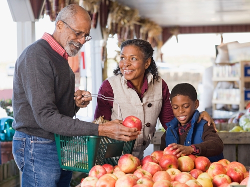 Family at produce market buying apples.